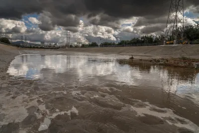 Low view of Glendale Narrows section of Los Angeles River with concrete bottom and cloudy storm sky over head.