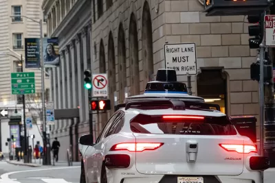 Close-up of back of white self-driving Waymo car on San Francisco street.