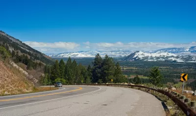 Curve in mountain highway along Teton Pass with snowy Wyoming mountains in background.
