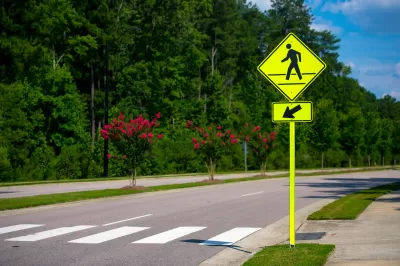 Yellow pedestrian caution sign next to a zebra crosswalk.