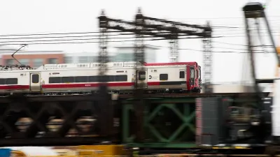 White and red train speeding past on green elevated bridge in Norwalk, Connecticut.