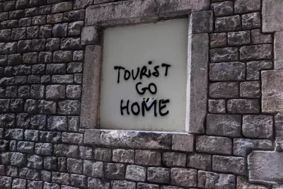 Spray painted words "Tourist Go Home" on wall in Barcelona illustrate locals' frustration with overtourism.