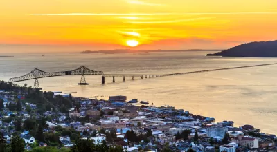 Aerial view of coastal town of Astoria, Oregon with suspension bridge and sunset sky.