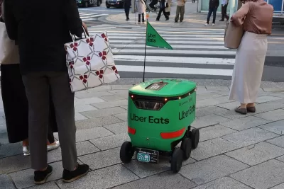 Green Uber Eats delivery robot waits at crosswalk in Tokyo, Japan.