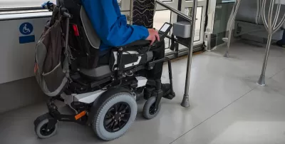 Man in wheelchair in designated area on public bus.
