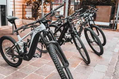 Black e-bikes sitting on a sidewalk outdoors.
