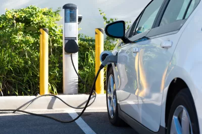 White electric car being charged in parking lot.