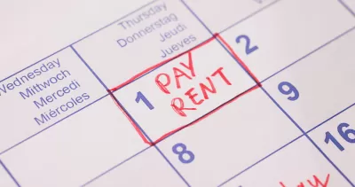 Close-up of 'Pay rent' note in red marker on day 1 of monthly calendar.