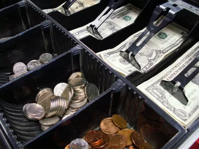 Close-up of cash drawer with various dollar bills and coins.