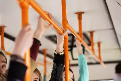 Close-up of hands holding straps on public bus.