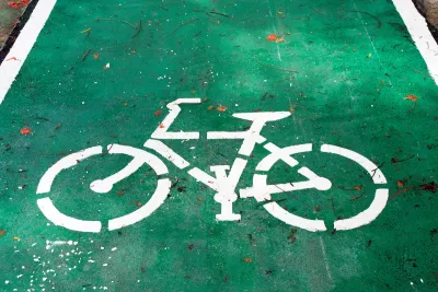 White bike symbol painted on green bike lane.