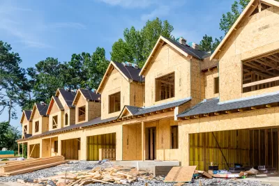 Wood-frame two-story rowhouses under construction.
