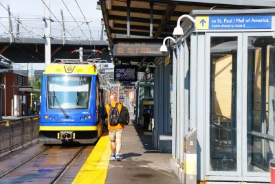 Outdoor train platform for light rail train in Minneapolis, Minnesota with passenger walking toward blue and yellow train.