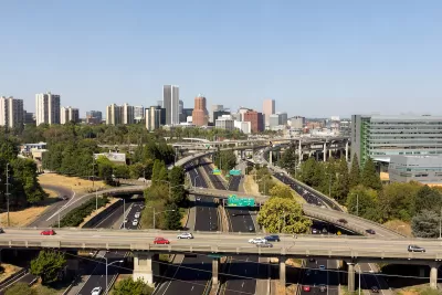 Aerial view of highway overpasses with Portland, Oregon skyline in background.