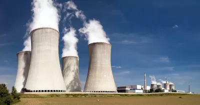 Nuclear power plant with four massive towers emitting white vapor.