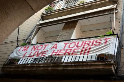Banner reading "I'm not a tourist - I live here!!!" hung on balcony in Barcelona, Spain.