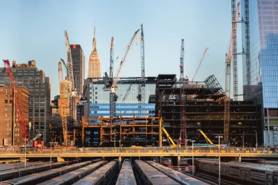 Construction site and cranes in New York City with Empire State Building visible in background.