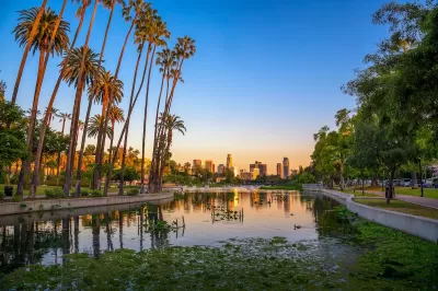 View of downtown Los Angeles at dusk with Echo Park lake and palm trees in foreground.