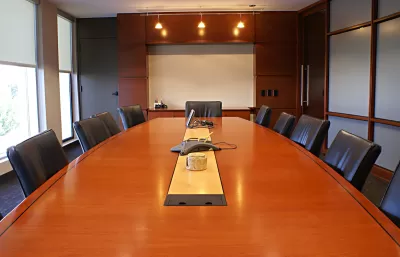 Large brown wood conference table surrounded by black leather chairs.