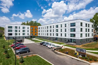 Four-story white L-shaoped apartment building with small parking lot in front in Edina, Minnesota