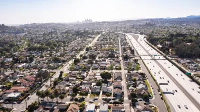 The Interstate 10 freeway cuts through residential neighborhoods in the city of Alhambra. Downtown Los Angeles is visible in the background,
