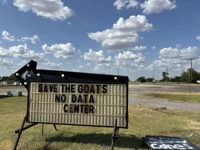 A sign in a field that reads "Save the goats, no data center"
