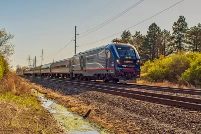An Amtrak passenger train is shown on a spring day, rolling through a rural area in Missouri.