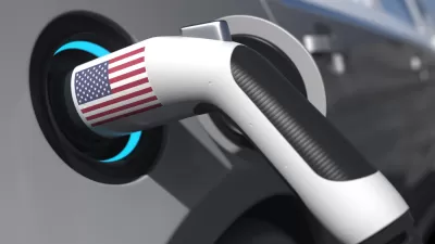 An electric vehicle charger with an American flag sticker is shown plugged into a car.