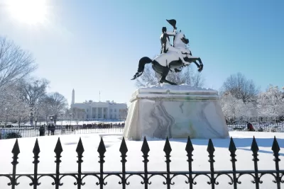 A snow covered statue looks out over a blanket of snow at the White House, which is also covered in snow.