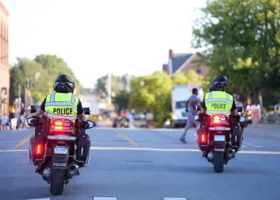 Two Ann Arbor police officers on motorcycles wearing bright yellow reflective vests with POLICE on back.
