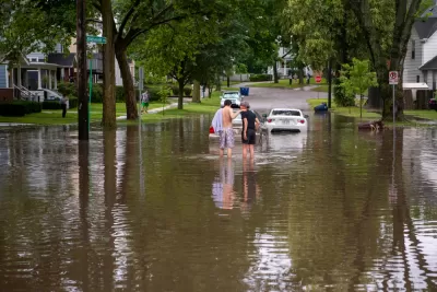 Two people walk down a residential street in ankle high water after a summer-time flood in Ann Arbor.