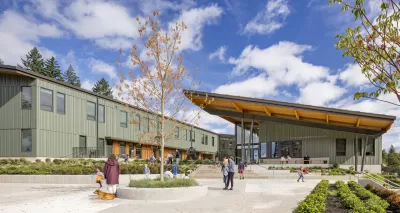 Green u-shaped school building with slanted roof and courtyard in the middle