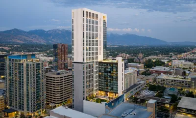 High-rise building with white top floors in downtown Salt Lake City, Utah with mountains in background.