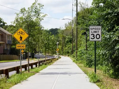 Paved Atlanta Beltline trail segment next to street with bike and pedestrian crossing sign and 30 mph speed limit sign.