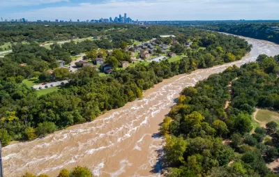The Colorado River is flooded with brown water with the skyline of Austin, Texas in the background.