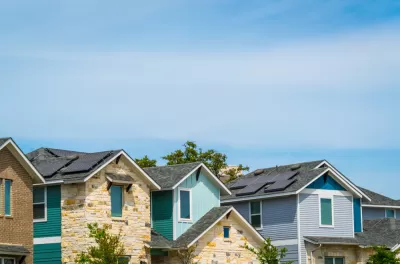 A row of homes, some brightly colored, on a sunny day in Austin, Texas.