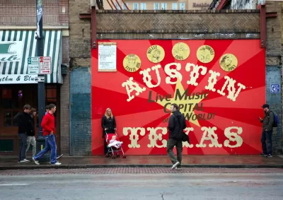 A woman with a baby in a stroller and two men are milling around in front a sign that reads Austin Texas: Live Music Capital of the World.