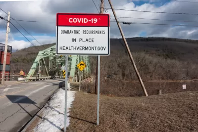 An image of a bridge in Vermont with a sign in front of it announcing a COVID-19 quarantine order.