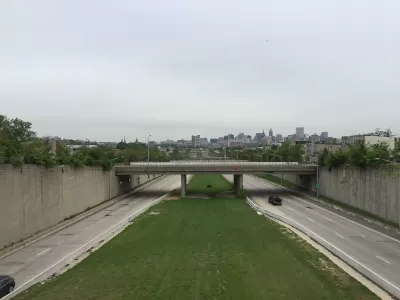 View from overpass of highway with one truck and green median with Baltimore city in the background