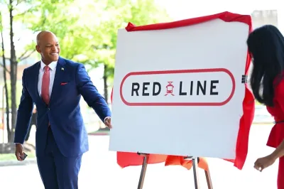 Maryland Governor Moore stands in front of a board with "Red Line" train logo.