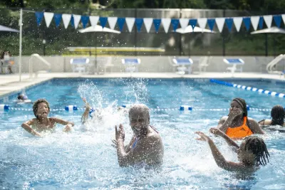 An older Black man and two Black children play in a newly-renovated Baltimore pool.