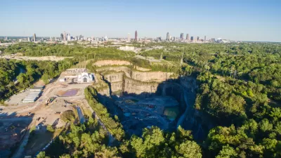 A massive hole in the ground, the Bellwood Quarry, is pictured with Downtown Atlanta rising above the horizon in the background.