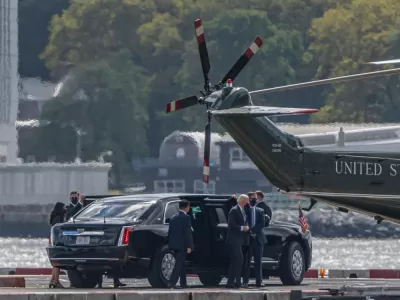 Joe Biden exits a limousine, surrounded by security and staffers, on the way to the Marine One helicopter on a pad near the water in New York City.