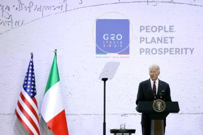 President Joe Biden speaks at a podium in front of flags from the United States and Italy at the 2021 G20 conference in Rome, Italy. 