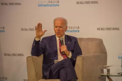 Joe Biden sits in a chair holding a microphone in front of a screen that reads Wall Street Journal and Infrastructure