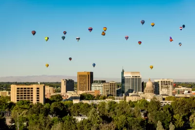 Hot air balloons rise over Downtown Boise with the State Capitol building visible amidst the high rises.