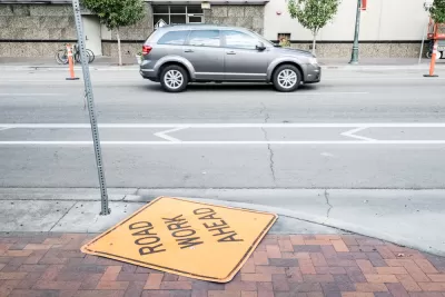 A "Road Work Ahead" lies neglected on the ground next to a street in Boise, Idaho.