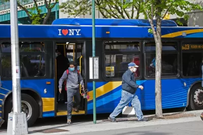 two riders wearing masks during the covid-19 pandemic exit a blue city bus in the Bronx in New York City.