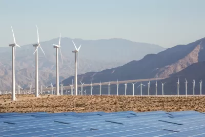 Wind turbines and solar panels against a backdrop of mountains in the Mojave Desert near Palm Springs, California