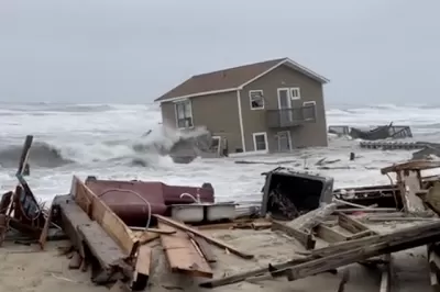 A house has been swept into the Atlantic Ocean by high tides, leaving ruins in onshore as the house appears half submerged by water,